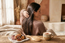 Femme aux cheveux longs et brillants avec des champignons reishi et chaga et une boisson aux champignons adaptogènes