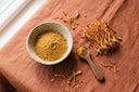 Cordyceps séché et poudre de cordyceps dans un bol en céramique sur un linge terracotta